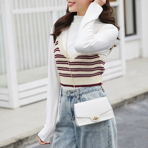 White crocodile pattern crossbody chain bag with golden lock shown on a model