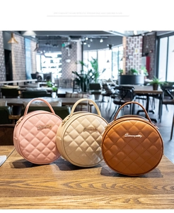 Détail de trois mini sacs à main ronds matelassés en rose, crème et marron sur une table