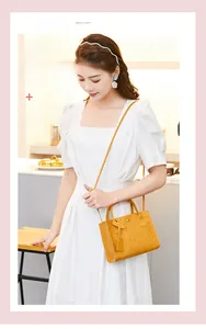 Yellow embossed Kelly bag with cartoon patterns worn by model in a stylish cafe setting
