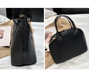 Detail of black shell bag with fine texture, golden chain strap and curved zipper closure