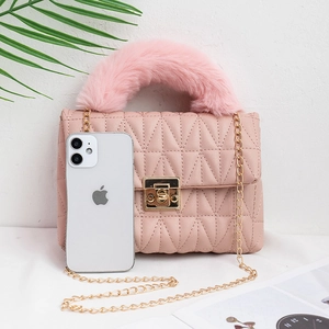 Pink quilted crossbody bag with faux fur handle and gold chain strap shown with phone