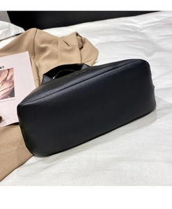 Close-up of black lychee grain leather handbag with wide base and fine stitching detail