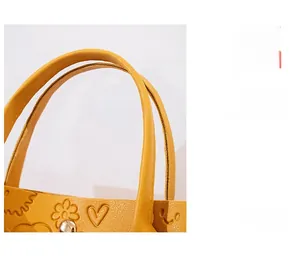 Detail of yellow pebbled faux leather tote bag showing reinforced handles and stitching