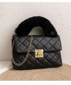 Détail d'un sac à main matelassé noir avec poignée en fourrure et chaîne dorée