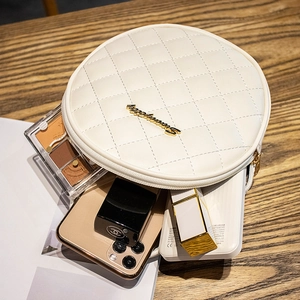 Mini sac rond blanc matelassé avec logo doré sur une scène de table en bois