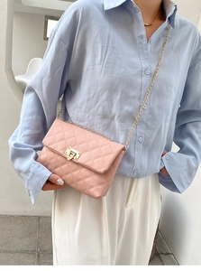 Detailed view of pink quilted crossbody bag with gold chain strap on female model