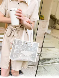 Detail shot of transparent PVC tote bag with white cosmetic prints and cream handles
