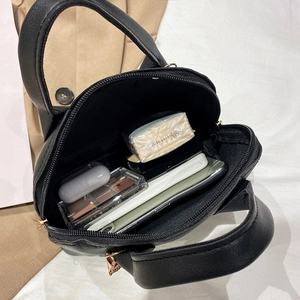 Minimalist black shell handbag in lychee leather showing interior storage for essentials