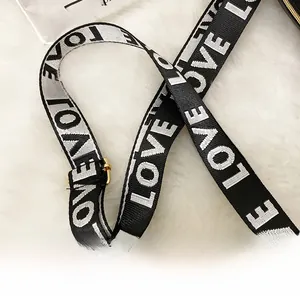 Détail de la bandoulière tissée noir et blanc motif LOVE avec boucles dorées