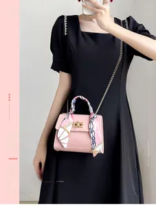 Pink crossbody bag with gold lock and floral silk scarf wrapped around the handle