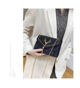 Detail of blue sequined crossbody bag with golden deer head clasp and chain strap