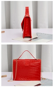 Detail view of red crocodile-pattern square bag with pearl chain and golden hardware