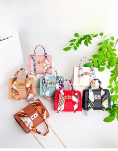 Flat lay of small crossbody bags in six colors featuring silk scarf handles and gold locks