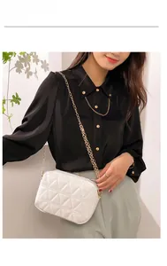 Chic white quilted square bag with gold chain strap worn over a black shirt