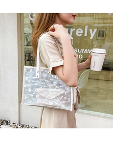 Close-up of PVC transparent tote bag with white cosmetic print and cream inner pouch