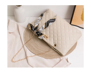 Detail of beige quilted chain bag featuring floral silk scarf and gold twist lock clasp