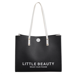 Minimalist black tote bag with white lettering and gold rivet shoulder strap detail