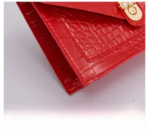 Detail of red crocodile texture with gold metal buckle and pearl decoration on handbag
