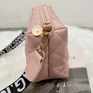Borsa a tracolla trapuntata rosa con cinturino stampato su un morbido tappeto bianco