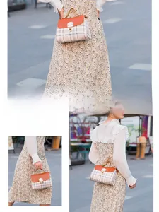Detail of classic plaid tote bag with orange leather flap and golden twist lock closure