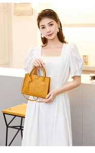Detail of yellow embossed tote bag with cartoon patterns and adjustable shoulder strap