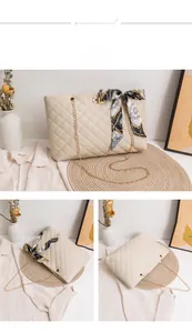 Detail of khaki quilted chain bag featuring a decorative printed silk scarf and gold lock