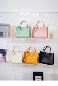 Close-up of five embossed PU leather handbags in mint, pink, beige, yellow, and black