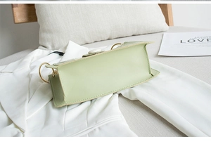 Detailed view of light green crocodile pattern bag on white blazer with metal rings