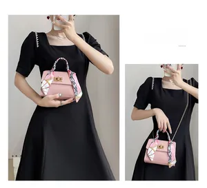 Pink pebbled leather handbag with decorative silk scarf and gold chain shoulder strap