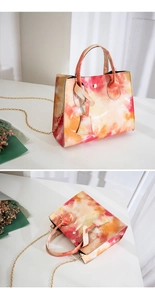 Detail of crossbody bag with pink and orange tie-dye print and gold chain strap