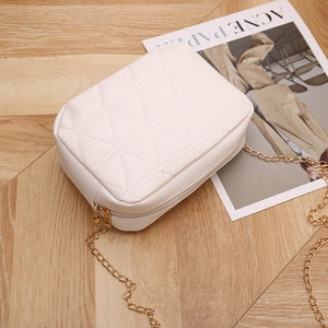 White quilted chain shoulder bag with geometric embroidery on a stylish wooden surface
