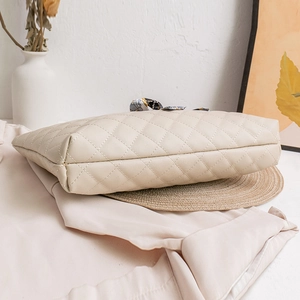 Quilted beige handbag with chain strap and printed silk scarf detail in a home setting