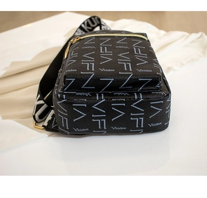 Macro view of black leather chest bag featuring white logo print and golden metal zipper