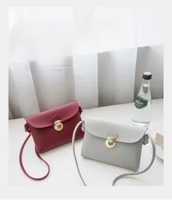 Detail of square cross-body bags in burgundy and light grey with golden circular clasps