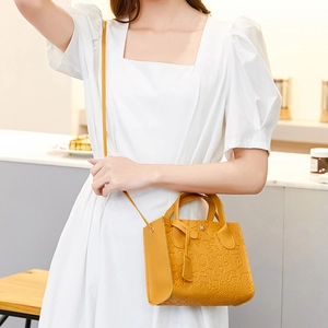 Yellow embossed tote bag with cartoon patterns and shoulder strap shown on a model