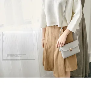 Detail of light gray PU leather crossbody bag featuring a golden metal twist lock closure