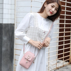 Pink woven mini crossbody bag with pearl charms and cat ear ring on model in white dress