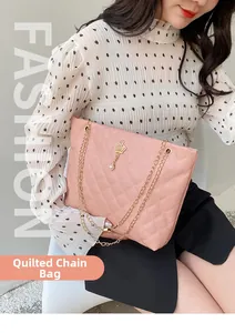 Pink quilted chain bag detail with gold crown pendant and pearl charm on a lady