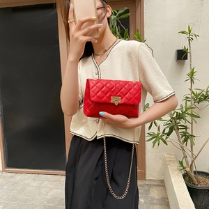 Red quilted crossbody bag with gold leaf chain strap shown on a model outdoors