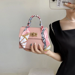 Pink square handbag with silk scarf wrapped handle and gold lock hardware