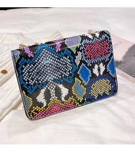 Detailed macro view of colorful snakeskin pattern and gold chain strap on shoulder bag