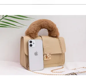 Close-up of cream crossbody bag with brown faux fur handle and gold chain strap