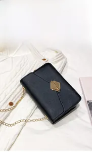 Detail of black mini crossbody bag with textured leather and gold hexagonal clasp