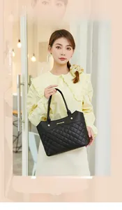Detail of a black quilted tote bag with golden logo lettering and reinforced handles