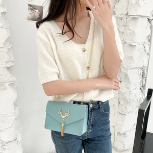 Light blue crossbody flap bag with a golden deer head charm and long tassel chain strap