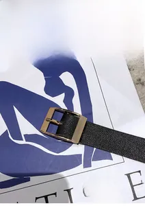 Détail de la ceinture réglable en cuir noir grainé avec boucle carrée dorée de luxe