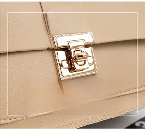 Close-up of golden rotating metal lock on beige lychee pattern leather handbag