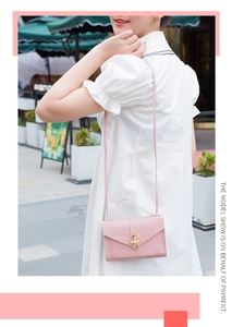 Pink croc-embossed mini bag with pearl gold clasp worn by a model in outdoor setting