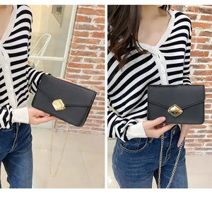 Close-up of black crossbody chain bag with a textured finish and golden hexagonal lock