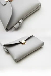 Detail of light grey PU crossbody bag showing litchi texture and knotted strap design
